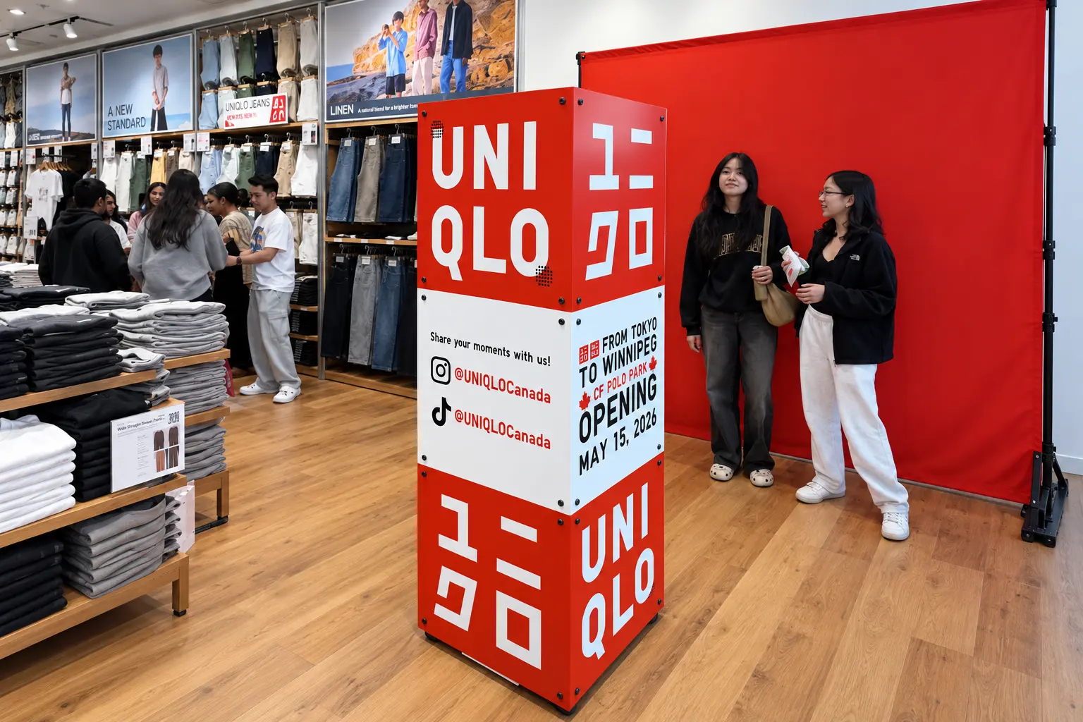 Custom red-and-white UNIQLO photo booth beside a red backdrop inside the CF Polo Park store